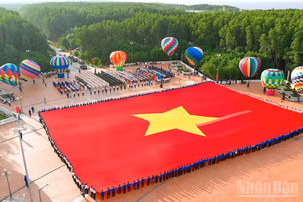 Toàn cảnh lá cờ Tổ quốc trải rộng tại sân Cột cờ Hà Nội ở Đất Mũi, chung quanh là các khinh khí cầu rực rỡ sắc màu. (Ảnh: HỮU TÙNG)