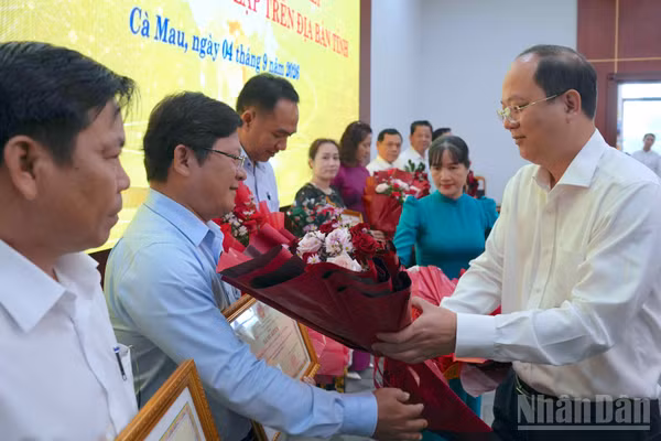 Đồng chí Nguyễn Hồ Hải, Ủy viên Trung ương Đảng, Bí thư Tỉnh ủy Cà Mau (bên phải) tặng hoa và Bằng khen của Chủ tịch tỉnh cho các tập thể, cá nhân có thành tích xuất sắc trong sắp xếp trường, lớp. (Ảnh: HỮU TÙNG)