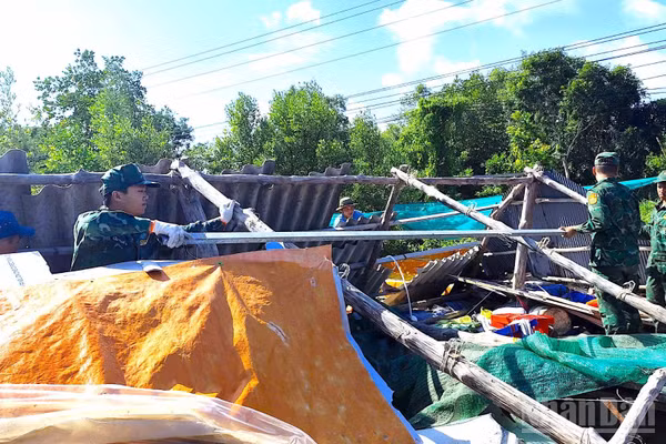 Cán bộ, chiến sĩ Đồn Biên phòng Đất Mũi, cùng các lực lượng tại chỗ hỗ trợ hộ ông Phan Chí Tâm khắc phục hậu quả thiên tai. (Ảnh: Hoàng Tá)