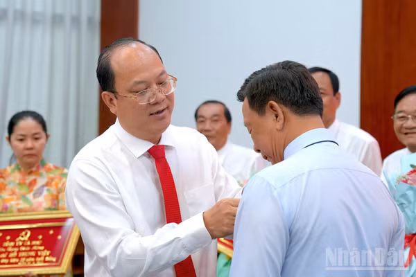 Đồng chí Nguyễn Hồ Hải, Ủy viên Trung ương Đảng, Bí thư Tỉnh ủy Cà Mau đeo Huy hiệu Đảng cho Đảng viên tại buổi lễ. (ảnh HỮU TÙNG).