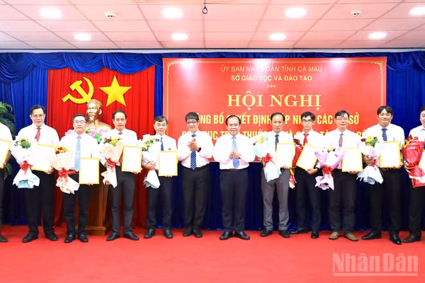 Phó Chủ tịch Ủy ban nhân dân tỉnh Cà Mau Nguyễn Minh Luân (thứ 6 từ phải qua) trao quyết định bổ nhiệm và tặng hoa các Hiệu trưởng Trường trung học phổ thông thuộc Sở Giáo dục và Đào tạo tỉnh. (Ảnh: HỮU TÙNG)