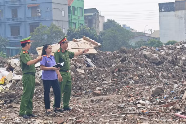 Lực lượng chức năng tại hiện trường, xác định diện tích và khối lượng chất thải xây dựng bị đổ trái phép. (Ảnh: Công an Hà Nội)