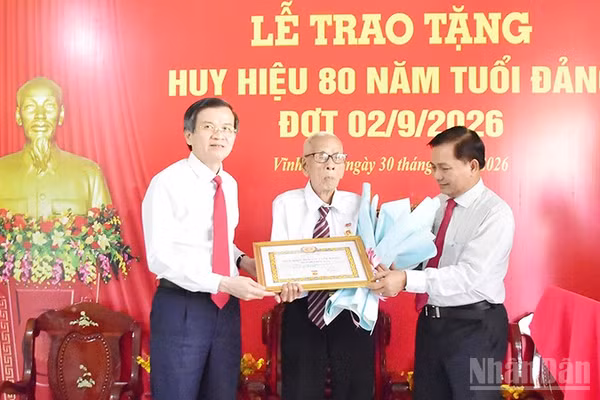 Đồng chí Huỳnh Long Tòa (giữa), Chi bộ ấp Nô Công, Đảng bộ xã Cầu Ngang, tỉnh Vĩnh Long nhận Huy hiệu 80 năm tuổi Đảng. (Ảnh: MINH KHỞI)