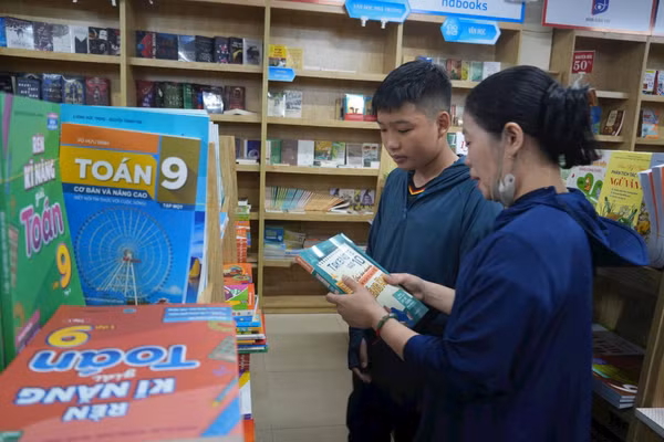 Nhiều gia đình lúng túng tìm mua sách giáo khoa cho con. Ảnh: Bích Huệ