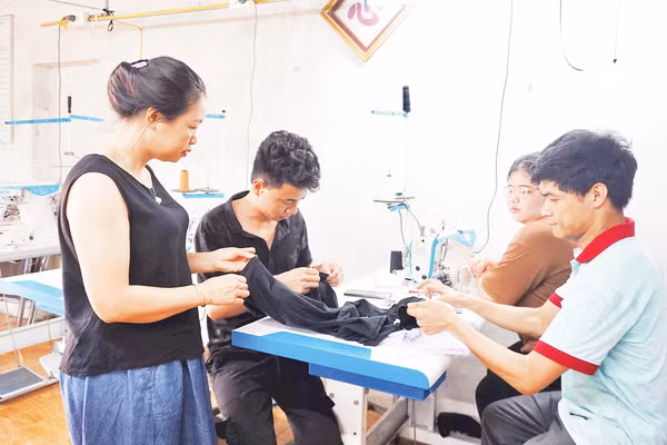 Chị Đinh Thị Quỳnh Nga (ngoài cùng, bên trái) hướng dẫn các bạn trẻ thực hành kỹ thuật cắt may. Ảnh: VĂN HỌC