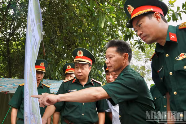 Thiếu tướng Nguyễn Ngọc Ngân và đoàn công tác cùng các nhân chứng lịch sử kiểm tra vị trí hài cốt liệt sĩ trên bản đồ. (Ảnh: THANH SƠN)