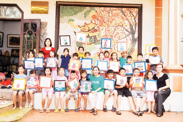 Họa sĩ Phan Thị Ngọc Mỹ (ngồi giữa) cùng các em nhỏ đến thăm và học vẽ tại Bảo tàng của bà.