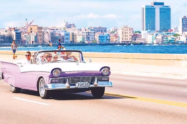 Du khách đi xe cổ ngắm thủ đô La Habana. (Ảnh: KIMKIM.COM)