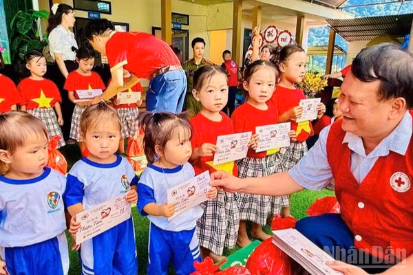 Lãnh đạo Hội Chữ thập đỏ tỉnh Điện Biên trao quà tặng các cháu học sinh mầm non tại điểm Trường mầm non Ca Hâu. (Ảnh: LÊ LAN)