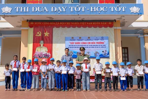 Các thành viên đoàn công tác tặng quà cho học sinh có hoàn cảnh đặc biệt khó khăn. (Ảnh: NHẬT QUANG)