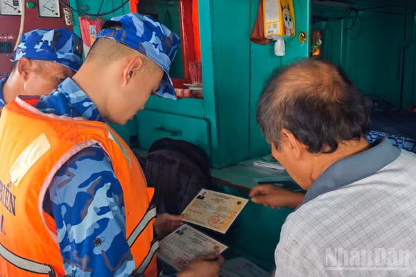 Tổ tuần tra, kiểm soát tiến hành kiểm tra giấy tờ tàu cá ngư dân đang hành nghề trên biển. (Ảnh: VĂN THƯỜNG)