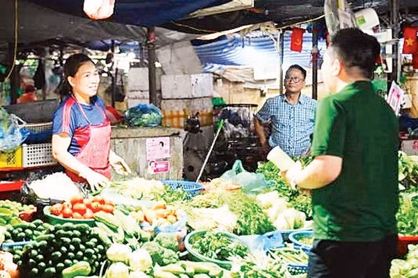 Tiểu thương tại chợ Đồng Xa (Hà Nội) được nhân viên VPBank hướng dẫn mở tài khoản hộ kinh doanh ngay tại quầy hàng. (Ảnh: MAI HẠ)