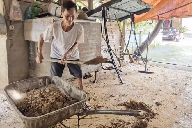 Ông Bùi Văn Nghiếp, tổ dân phố Sơn Hải thu dọn bùn đất còn đọng lại trên sân nhà. (Ảnh: TRỊNH LAN)