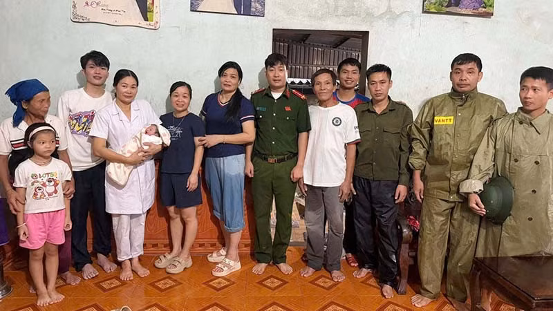 Lực lượng chức năng cùng gia đình vui đón trẻ sơ sinh trong mưa lũ. (Ảnh: Công an Thanh Hóa)
