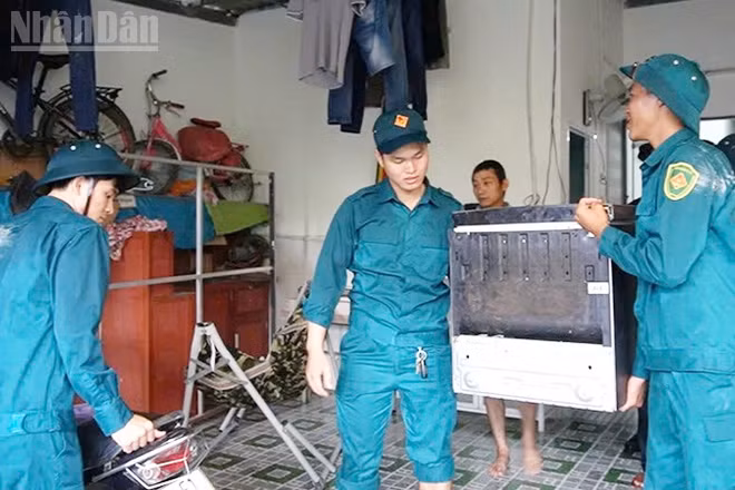 Lực lượng dân phòng hỗ trợ người dân vùng nguy cơ ngập lụt kê cao đồ đạc.