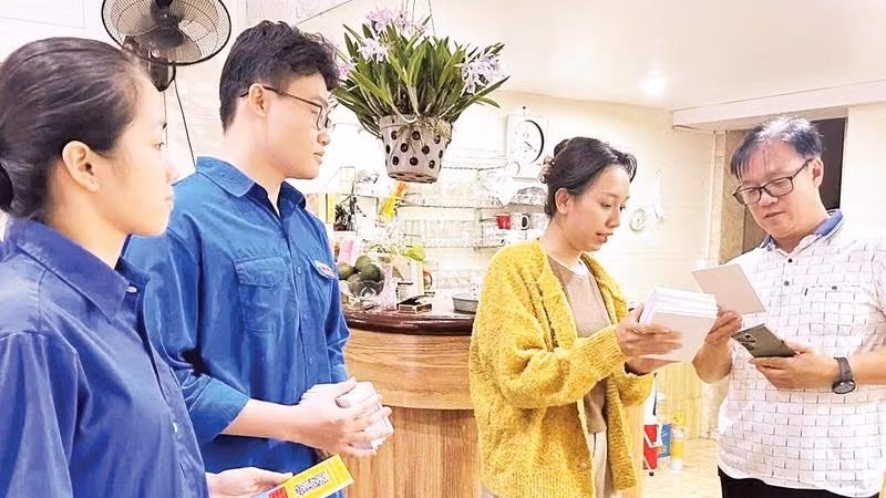 Thành viên tổ công nghệ số cộng đồng của phường Hồng Bàng hướng dẫn người dân sử dụng những tiện ích số (Ảnh HUY VŨ)