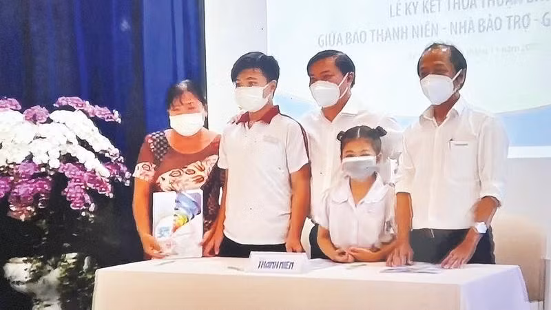 Đại diện Chương trình “Cùng con đi tiếp cuộc đời” trao suất bảo trợ cho em Lê Thị Ngọc Tuyết và em Lê Minh Khang có cha mất trong đại dịch Covid-19 (Ảnh BÁO THANH NIÊN)