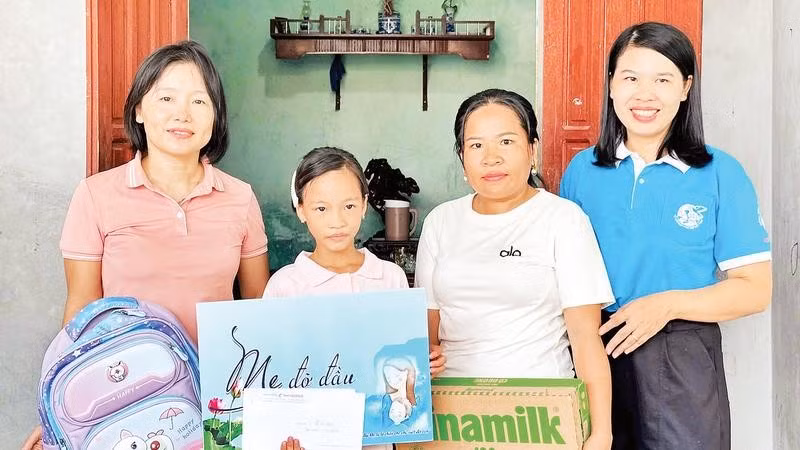 Cháu Hoàng Thị Linh Đan được chị Nguyễn Thị Ánh Tuyết (áo hồng) nhận làm con đỡ đầu từ khi vừa mất mẹ.