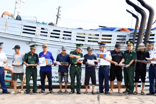 Bộ đội biên phòng Thành phố Hồ Chí Minh và Cảnh sát biển 3 phát tờ rơi tuyên truyền phòng chống IUU tại cảng cá Cát Lở. (Ảnh: Cảnh sát biển cung cấp) 