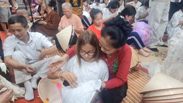 Nghệ nhân làng Chuông hướng dẫn du khách trải nghiệm các công đoạn làm nón tại không gian học tập cộng đồng ở đình làng Chuông.