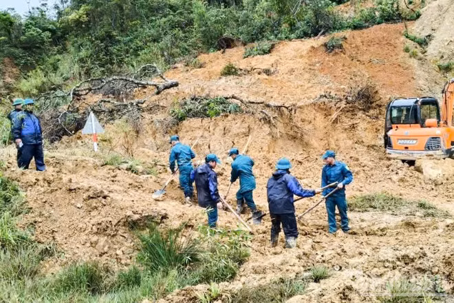 Lực lượng dân quân tự vệ xã Hùng Sơn khẩn trương dọn đất đá để khơi thông đường.
