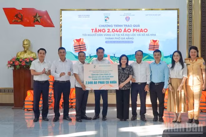 Lãnh đạo Bộ Nội vụ và Báo Dân Trí trao bảng tượng trưng tặng 2.040 áo phao cho người dân hai xã Đại Lộc và Hà Nha. (Ảnh: QV)