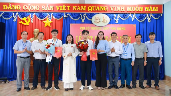 Bí thư Đảng ủy xã Phú Riềng cùng các đồng chí trong Chi bộ Trường trung học phổ thông Phú Riềng tặng hoa chúc mừng 2 đảng viên mới.