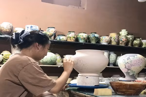 Vẽ hoa văn trên gốm tại một xưởng sản xuất gốm xã Bát Tràng, thành phố Hà Nội. (Ảnh: HÀ ANH)