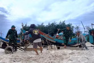 Cán bộ, chiến sĩ Đồn Biên phòng Roòn (Quảng Trị) giúp dân kéo, chuyển thuyền đánh cá lên bờ.