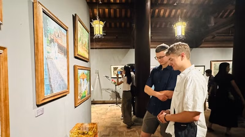 Khách quốc tế tham quan những tác phẩm về Quốc Tử Giám tại triển lãm.