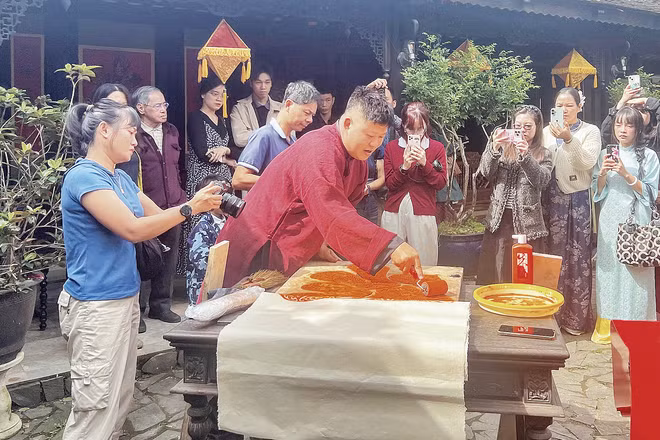 Nghệ nhân Nguyễn Công Đạt thực hiện in liễn làng Chuồn trong không gian Ngự Hà Viên, Huế. (Ảnh: MẠNH HÀO)
