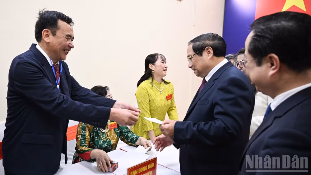 Thủ tướng Phạm Minh Chính nhận thẻ cử tri đóng dấu chứng nhận đã hoàn thành việc bỏ phiếu. (Ảnh: TRẦN HẢI)