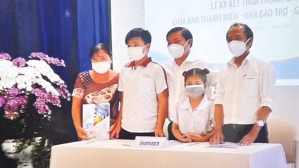 Đại diện Chương trình “Cùng con đi tiếp cuộc đời” trao suất bảo trợ cho em Lê Thị Ngọc Tuyết và em Lê Minh Khang có cha mất trong đại dịch Covid-19 (Ảnh BÁO THANH NIÊN)