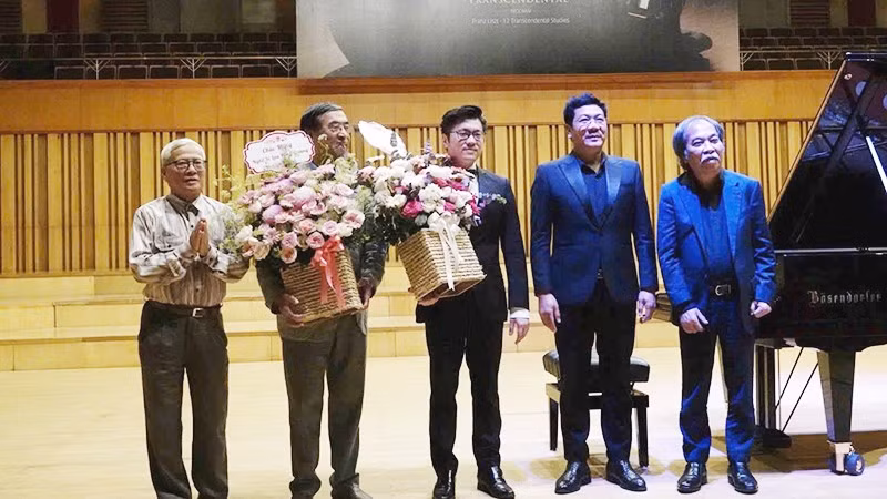 Đại sứ Nguyễn Thạc Dĩnh, đại sứ Nguyễn Phú Bình (từ trái sang) và nhà thơ Nguyễn Quang Thiều, TS, NSND Đỗ Quốc Hưng (từ phải sang) tặng hoa nghệ sĩ Lưu Hồng Quang sau màn trình diễn. Ảnh: NGUYỄN ĐÌNH TOÁN