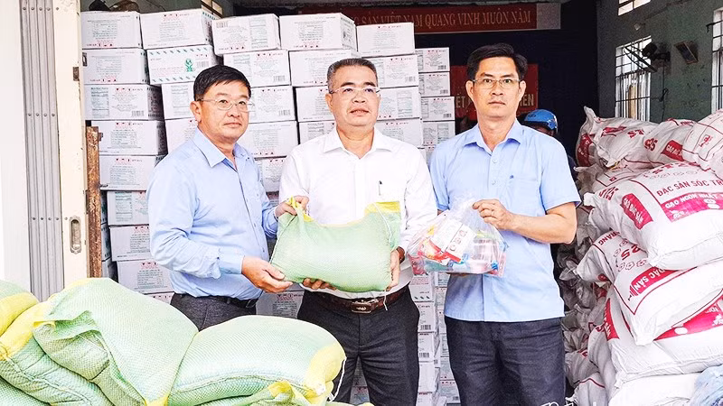 Nhà báo Lê Hoàng Triều (bên trái) trao quà hỗ trợ địa phương bị ảnh hưởng bởi mưa lũ.