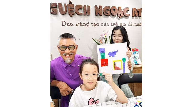 Họa sĩ Đào Hải Phong bên cạnh cháu Linh Chi (5 tuổi) với tác phẩm vui của cháu, cắt ảnh của họa sĩ dán vào tranh để tô vẽ.