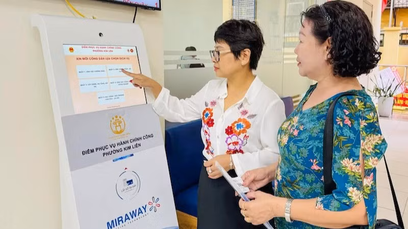 Công chức tại Điểm tiếp nhận, phục vụ hành chính công phường Kim Liên hướng dẫn người dân lấy số để thực hiện các thủ tục hành chính. (Ảnh: KHÁNH HUY)