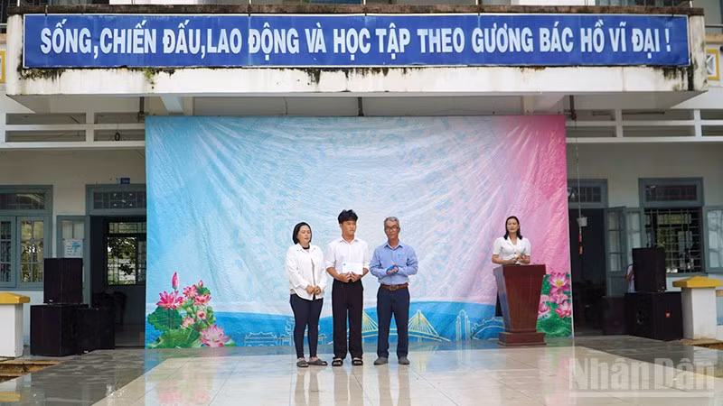 Em Trần Lê Nguyễn nhận tiền hỗ trợ của Quỹ xã hội Cỏ May tại sân trường.
