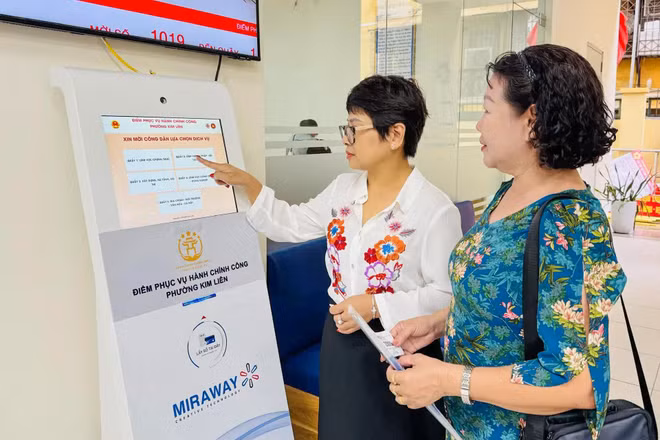 Công chức tại Điểm tiếp nhận, phục vụ hành chính công phường Kim Liên hướng dẫn người dân lấy số để thực hiện các thủ tục hành chính. (Ảnh: KHÁNH HUY)