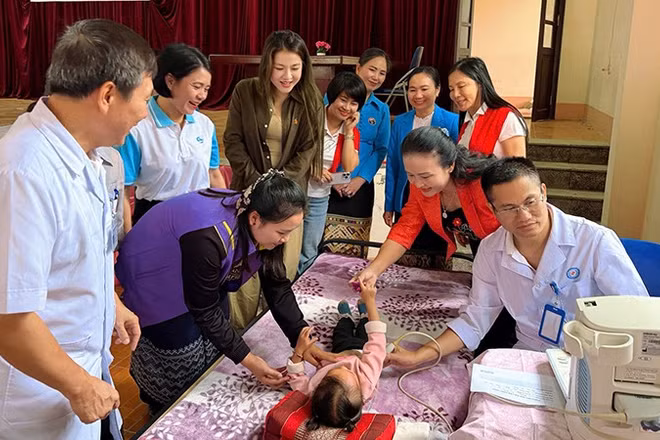 Phụ nữ cùng bác sĩ chăm sóc, khám bệnh cho trẻ em Lào.