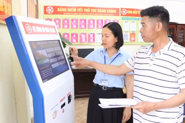 Công chức Trung tâm Phục vụ hành chính công xã Kim Thành, thành phố Hải Phòng, hướng dẫn người dân làm thủ tục hành chính. (Ảnh: TTXVN) 