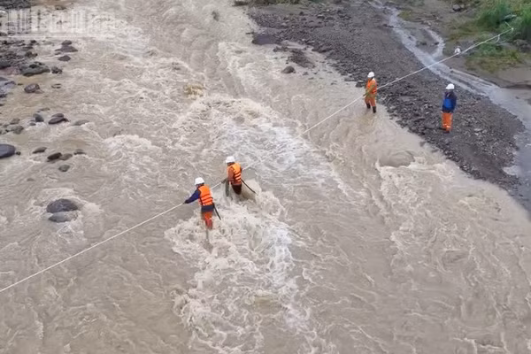 Cán bộ nhân viên Điện lực khu vực Mường La giăng dây vượt suối đến khu vực xảy ra sự cố về điện tại bản Hua Nặm, xã Mường La để khôi phục việc cấp điện.