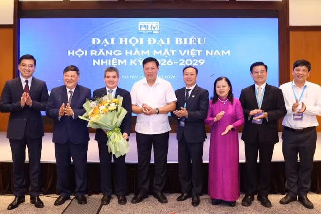 Thứ trưởng Y tế Đỗ Xuân Tuyên (áo trắng) chúc mừng tân Chủ tịch Hội Răng Hàm Mặt Việt Nam. (Ảnh: CTV)