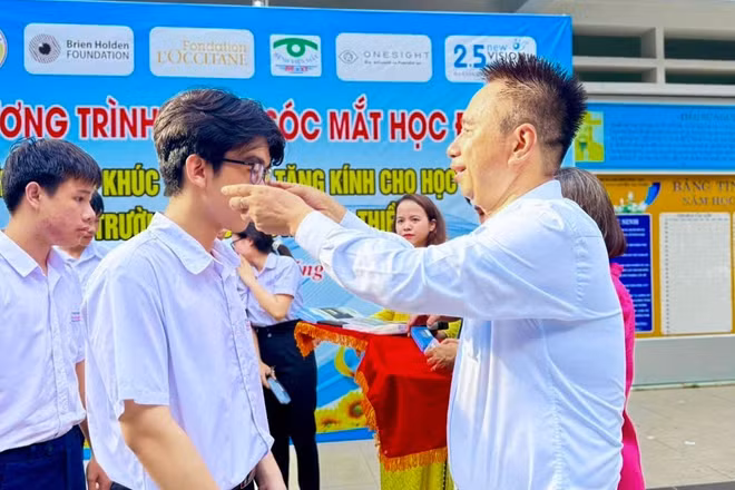 Bác sĩ Nguyễn Viết Giáp mang kính cho học sinh bị tật khúc xạ.