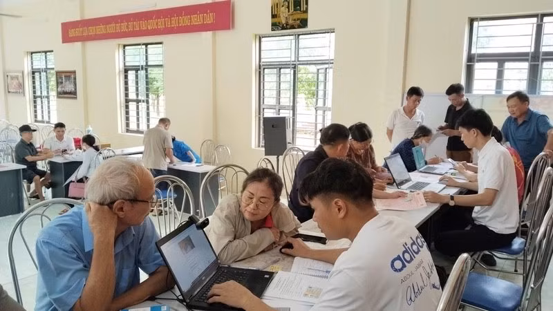 Cán bộ thôn Hồng Kỳ, xã Trung Giã (Hà Nội) hướng dẫn người dân cách sử dụng ứng dụng eTax Mobile, iHanoi và khai báo làm sạch dữ liệu đất đai. (Ảnh: LÊ TRƯỜNG) 
