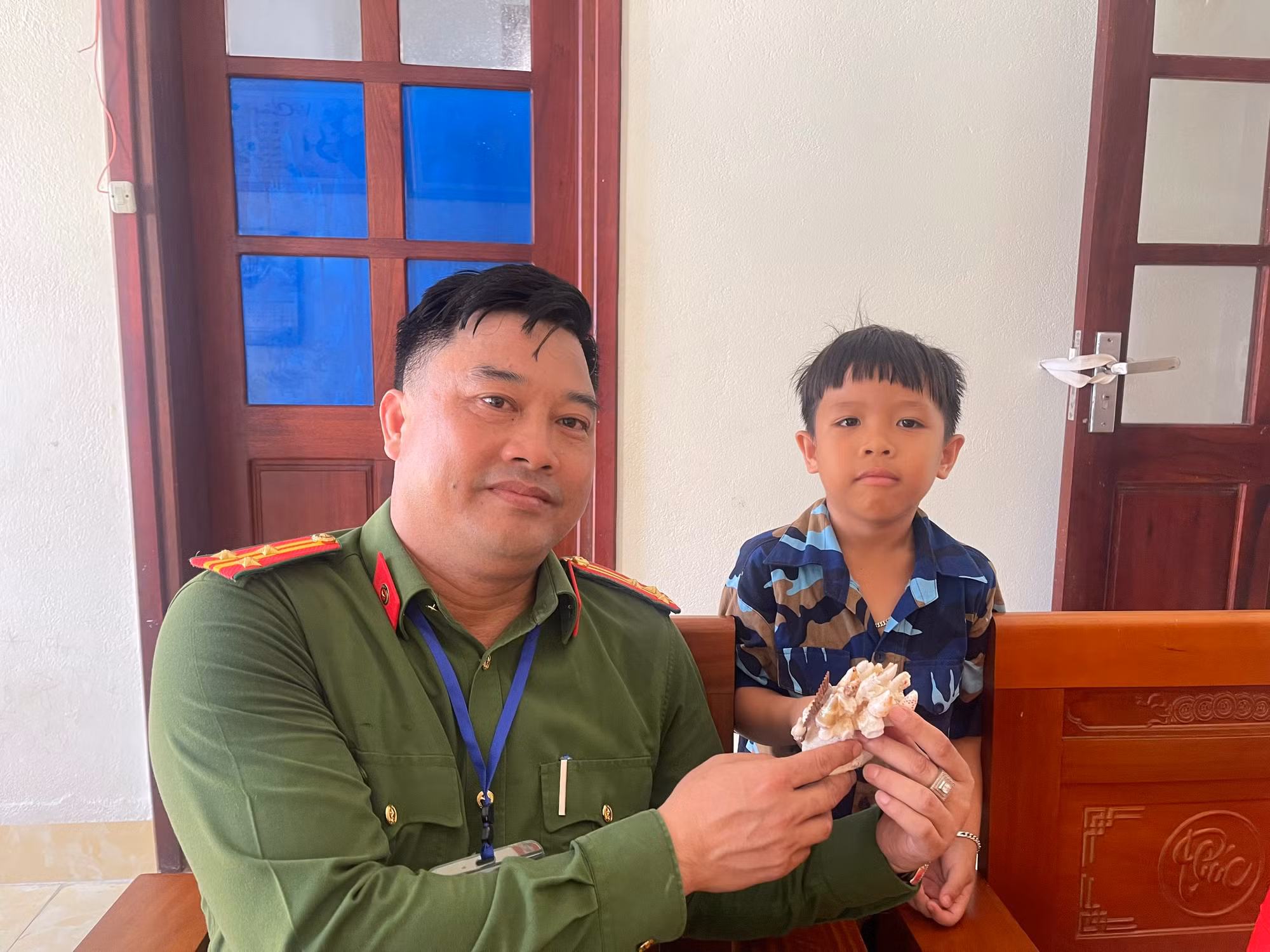 Cậu bé hiếu khách dành tặng món quà quý từ biển đảo cho các chú trong đoàn công tác.