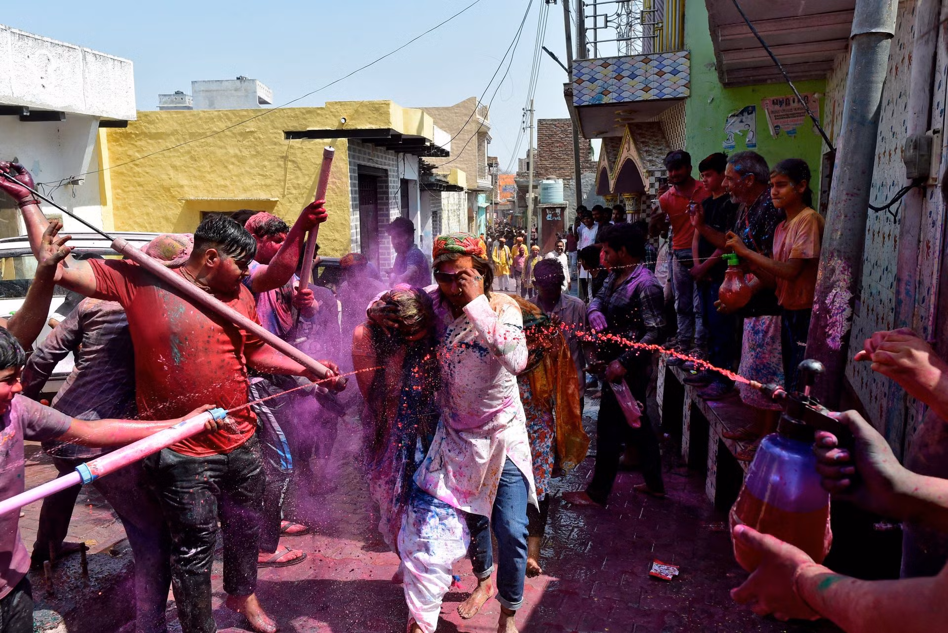 Người dân phun nước màu lên du khách trên một con đường nhỏ trong dịp Lễ hội Holi ở thị trấn Nandgaon, Uttar Pradesh, Ấn Độ. (Ảnh: Reuters)