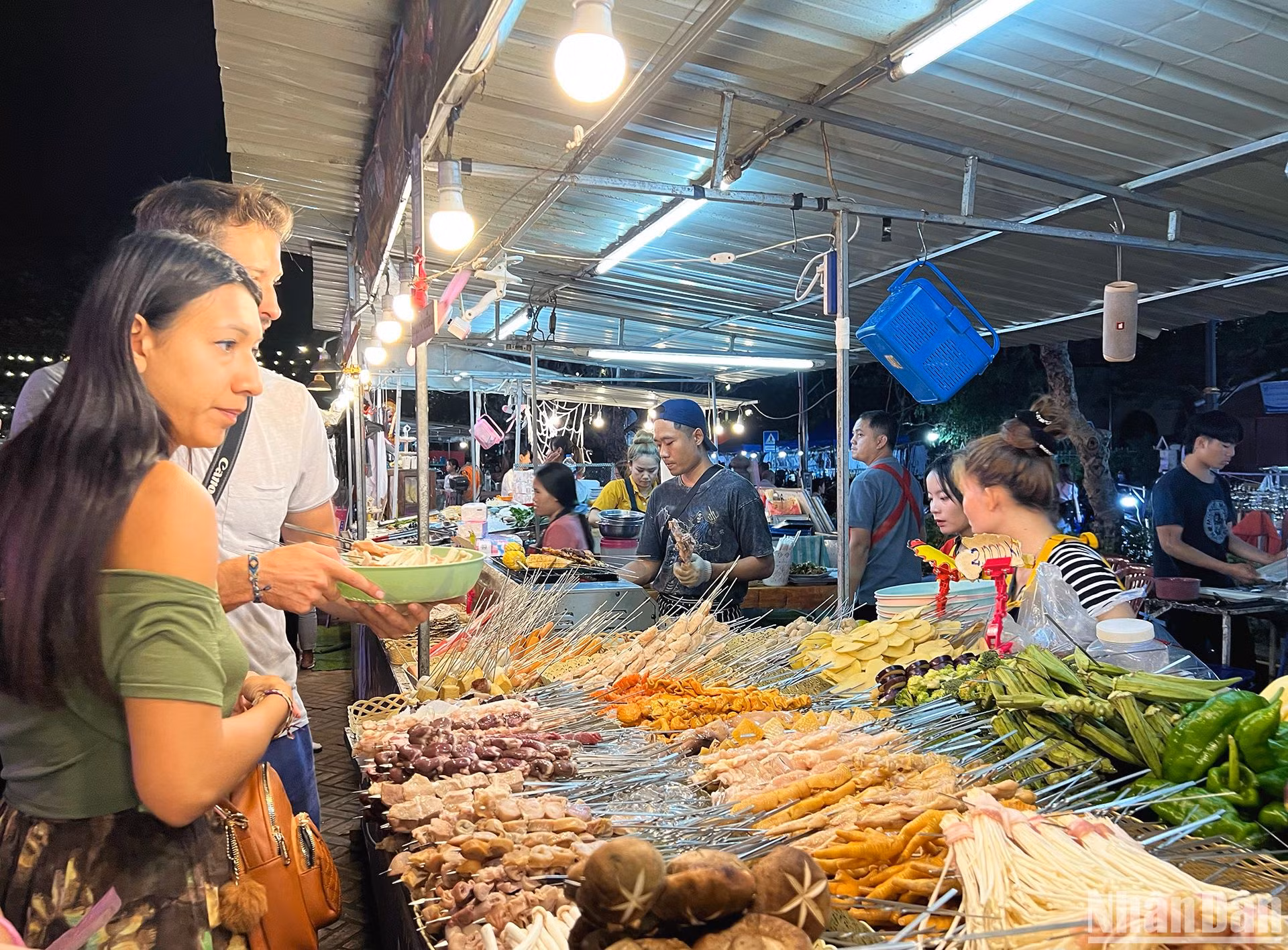 Du khách thích thú trải nghiệm các món ăn Lào truyền thống tại khu chợ đêm Luang Prabang. (Ảnh: TRỊNH DŨNG)