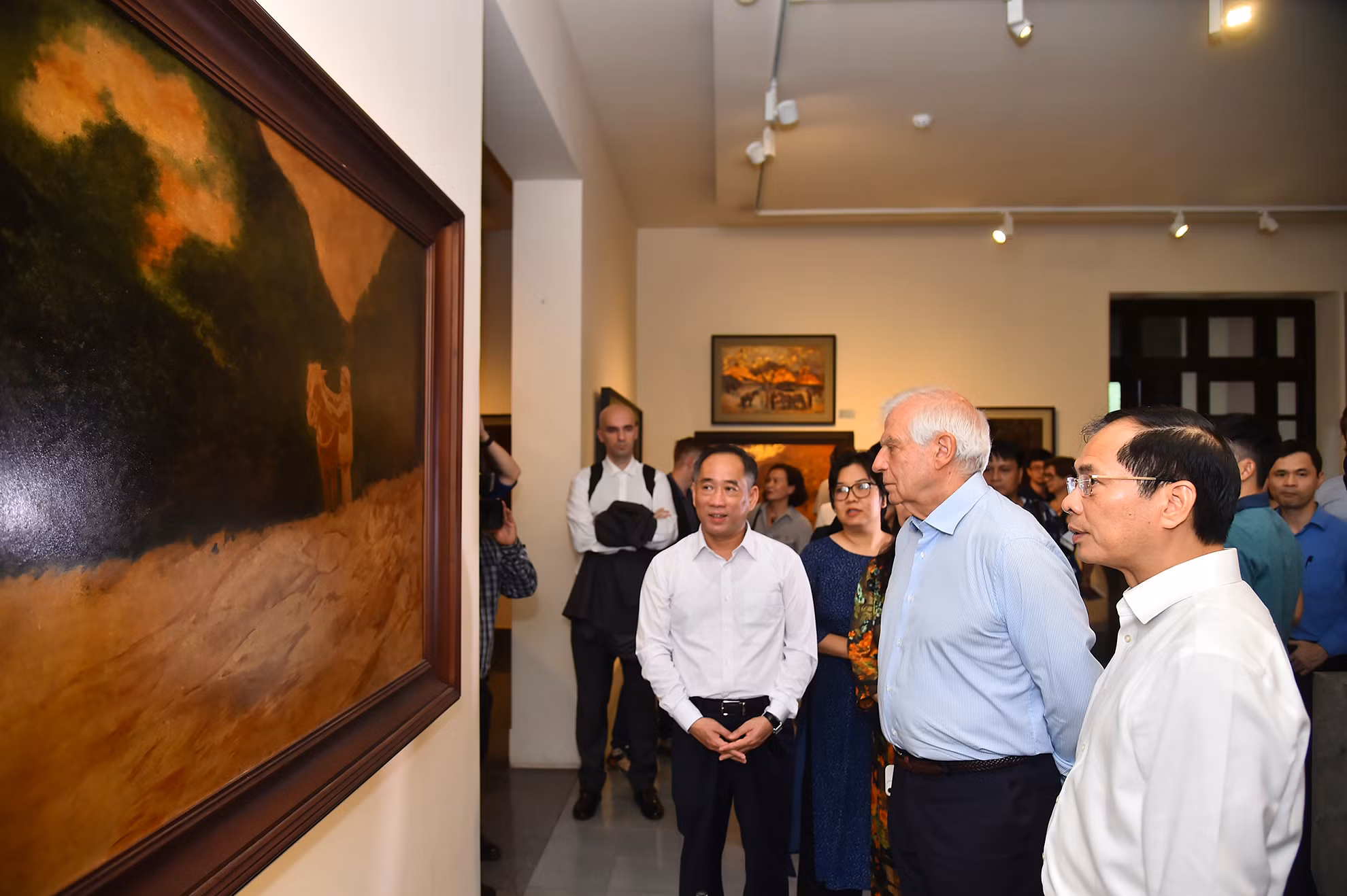 Bộ trưởng Ngoại giao Bùi Thanh Sơn và Phó Chủ tịch Ủy ban châu Âu Josep Borell Fontelles cùng các đại biểu chiêm ngưỡng và nghe giới thiệu về bức tranh "Bác Hồ ở chiến khu Việt Bắc" của họa sĩ Dương Bích Liên.