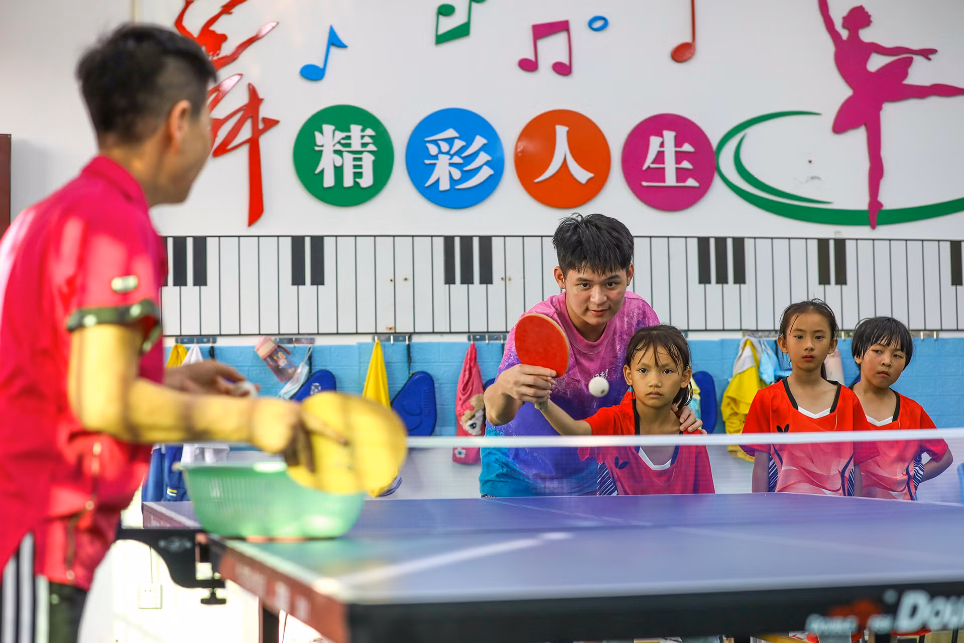 Vận động viên đội tuyển bóng bàn quốc gia Trung Quốc Lin Shidong dạy trẻ em cách giao bóng tại Trường trung tâm Shuiman ở thành phố Ngũ Chỉ Sơn, tỉnh Hải Nam. (Ảnh: China Daily) Vận động viên đội tuyển bóng bàn quốc gia Trung Quốc Lin Shidong dạy trẻ em cách giao bóng tại Trường trung tâm Shuiman ở thành phố Ngũ Chỉ Sơn, tỉnh Hải Nam. (Ảnh: China Daily)